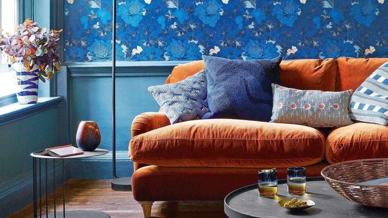 Living room with bold blue wallpaper and smart orange velvet sofa