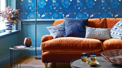 Blue living room with wallpapered wall and blue woodwork, plus orange velvet sofa