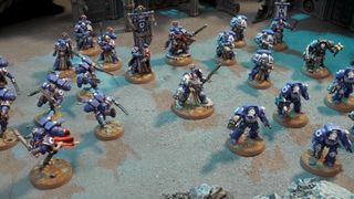 An array of Space Marines on a gray, rugged battlefield