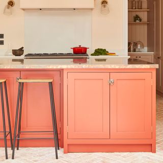 Pink-y red kitchen cabinets with terracotta floor