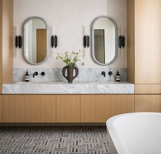 A bathroom with a marble and wood vanity, with a marble backsplash