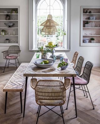 boho style dining room with parquet wood flooring, rattan seating, a bench and large dining table