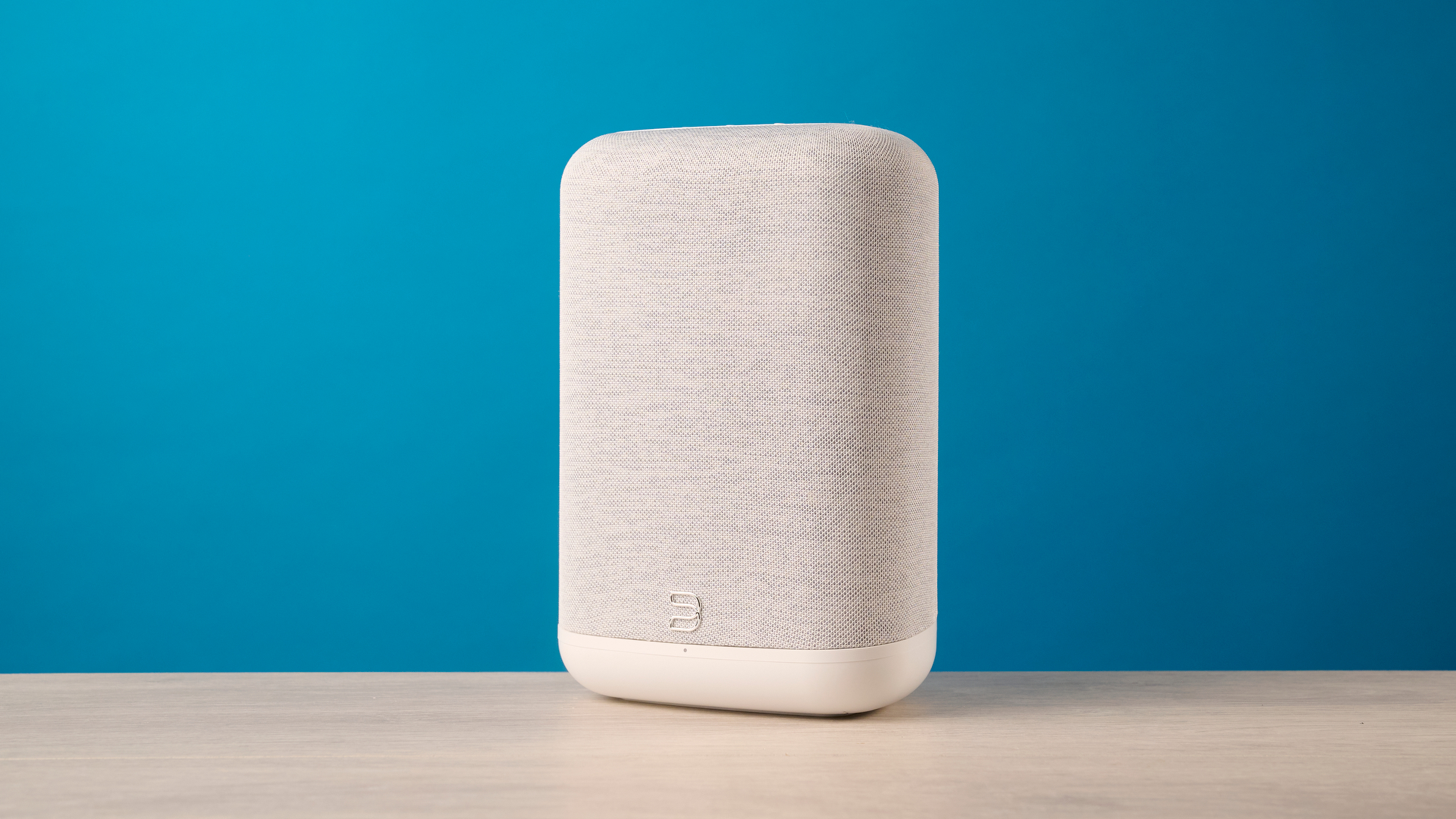 the bluesound pulse flex wi-fi speaker in pale gray photographed against the blue tom's guide background