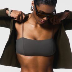 A model pulls on a shirt over her Reformation bikini top