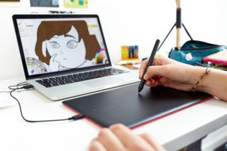 Person uses digital pen to draw on laptop computer.