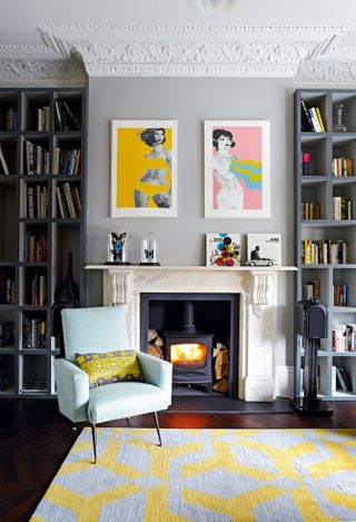 Grey living room with build in shelving, colorful artwork and yellow rug