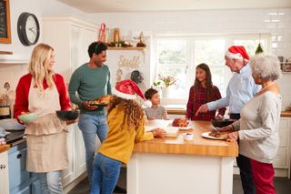 Multi-Generation Family In Kitchen Helping To Prepare Christmas Meal Together