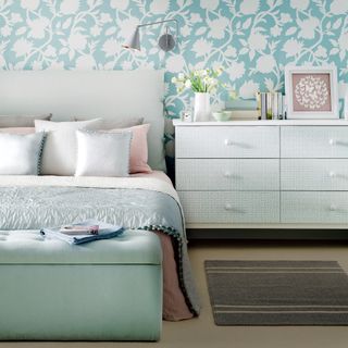 Soft blue bedroom with floral wallpaper and satin blue bedspread
