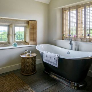 white bathroom with wooden windows and bathtub