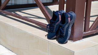 A pair of navy running shoes drying on a tiled patio