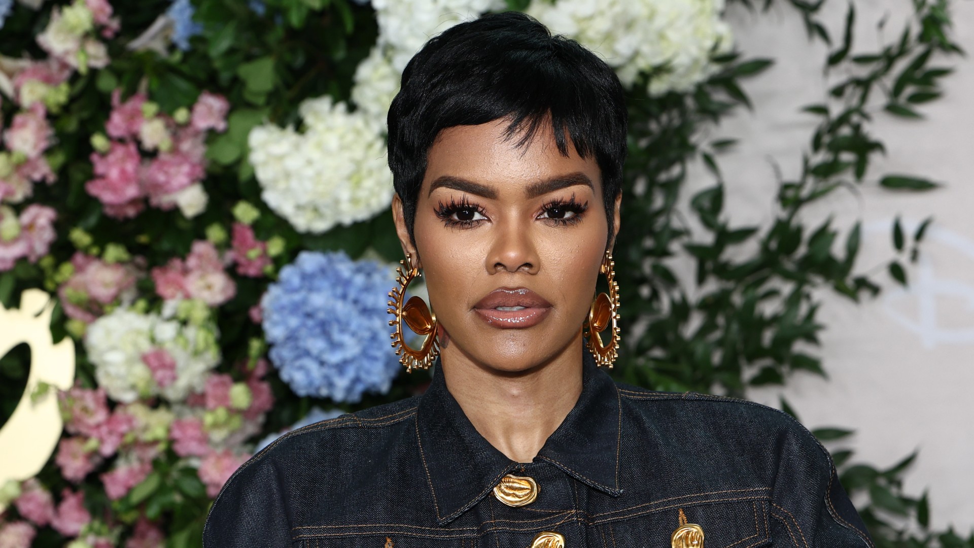 a black woman with short, black hair posing for paparazzi at a red carpet event