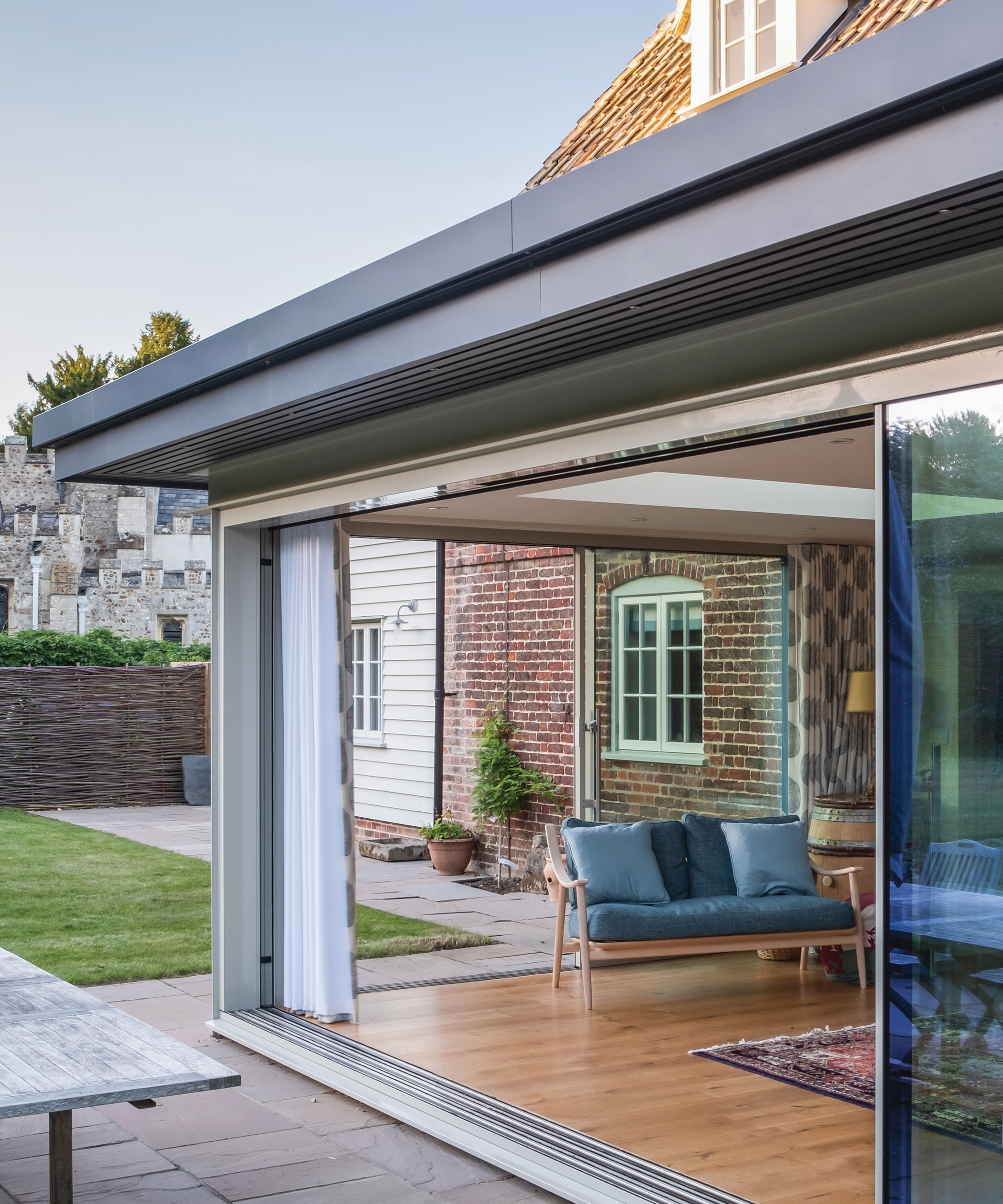traditional home with modern glazed extension featuring sliding doors leading out to a patio