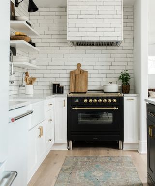 small white kitchen with black range cooker and vintage rug