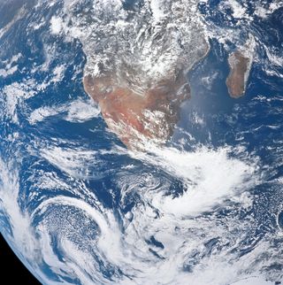 Image of Earth with white swirling clouds and blue oceans. The lower portion of the African continent is visible.