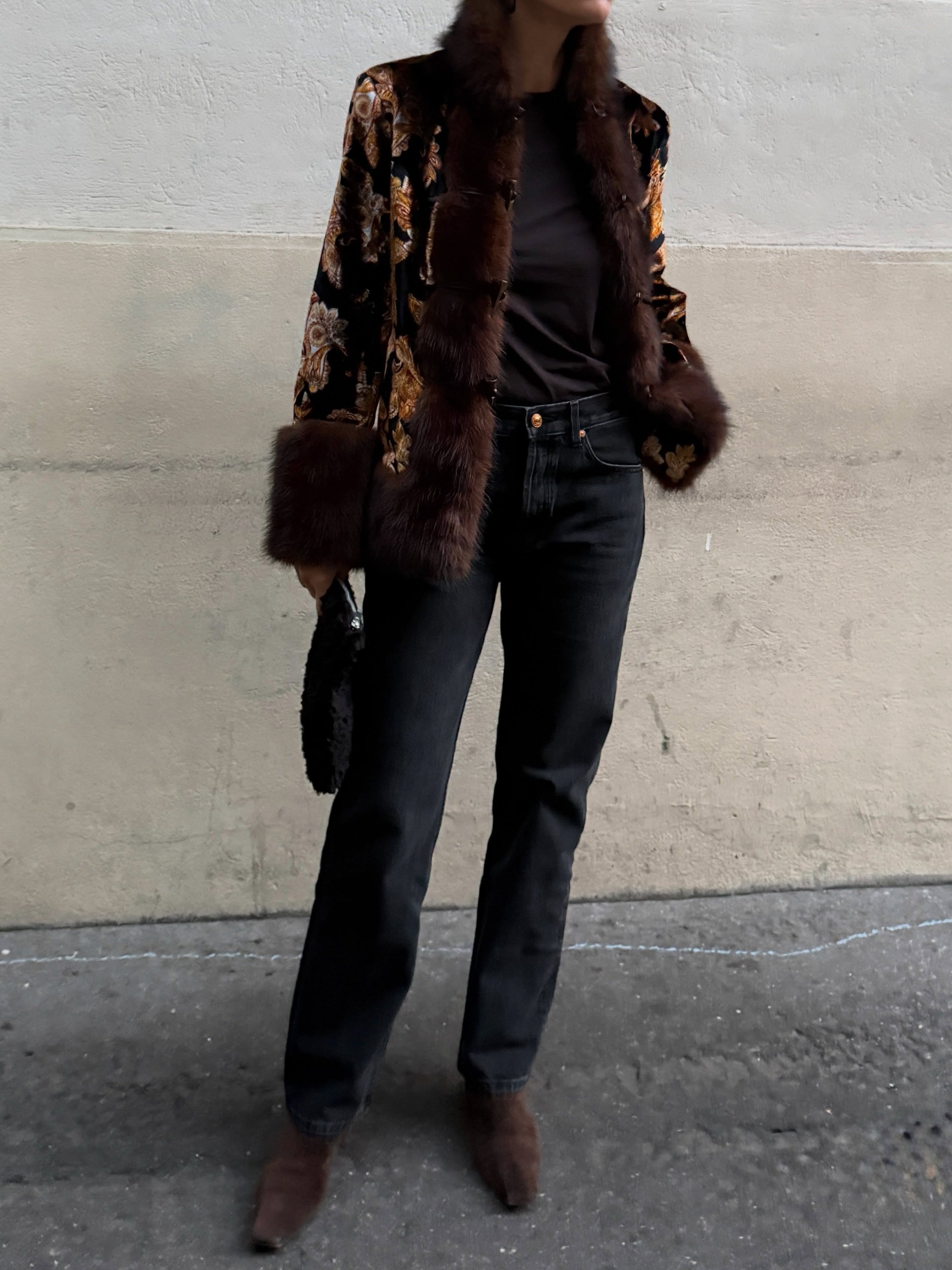 Woman in an opulent jacket and jeans.