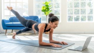 Pilates ab workout: Woman in a one-legged forearm plank following at-home pilates on a yoga mat