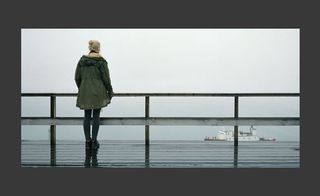 A woman standing facing the sea