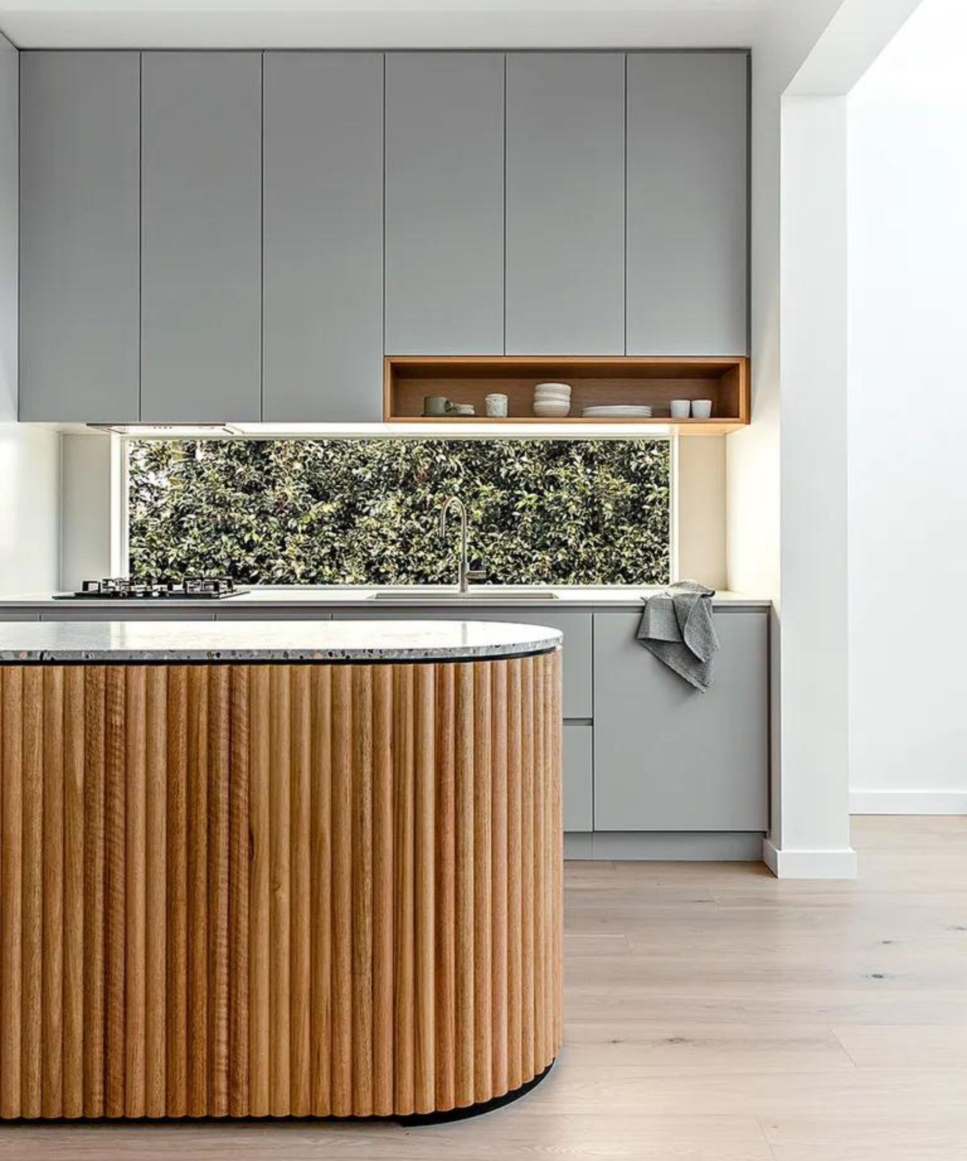 A gary kitchen with a curved kitchen island featuring a fluted paneling detail