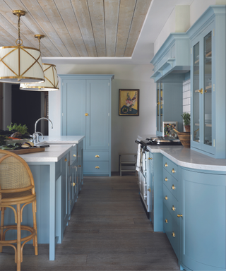 blue kitchen with dark wood floors and white marble tops