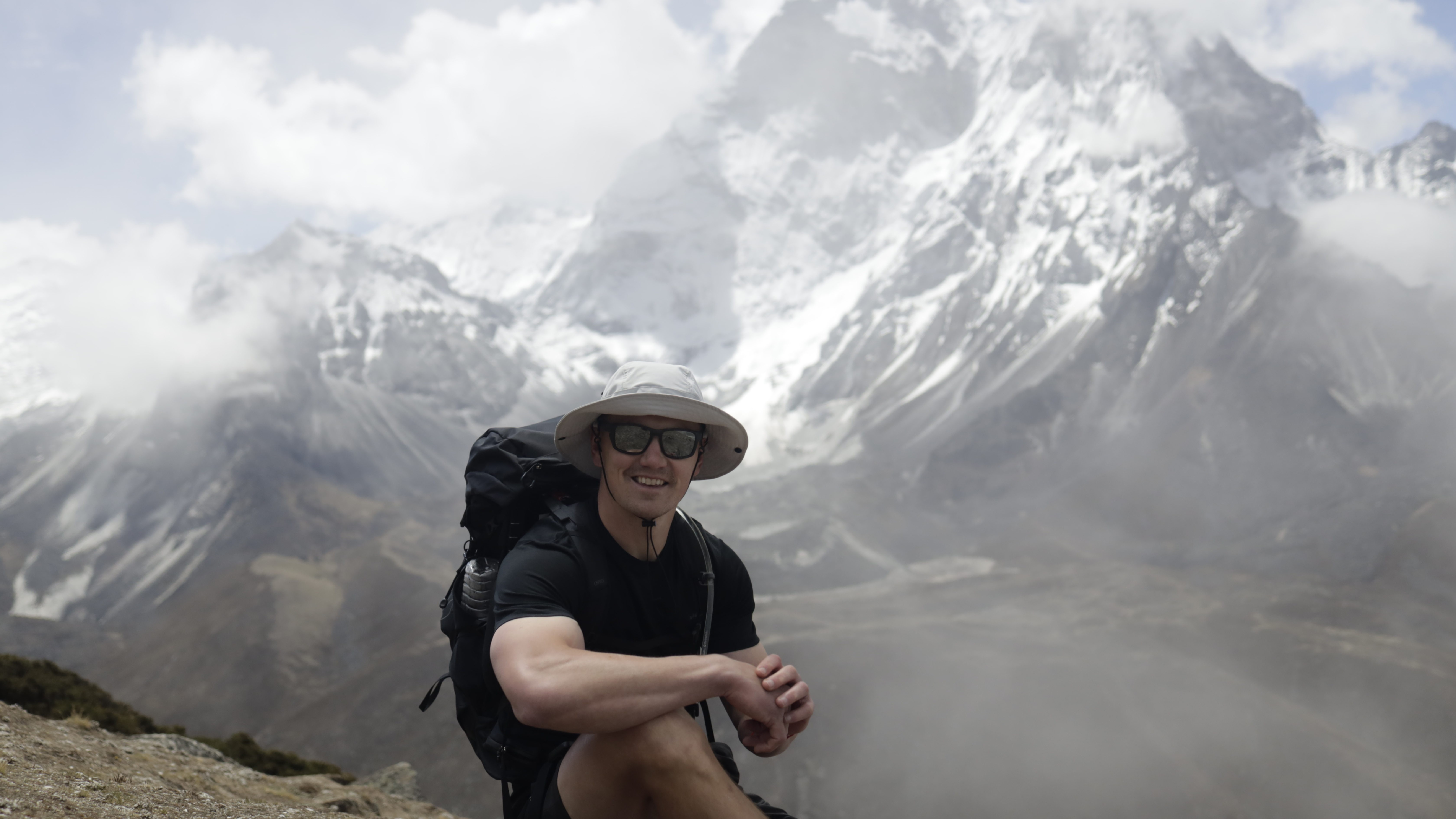 Jonathan Davies sits on a rock with a snowy Himalayan peak in the background