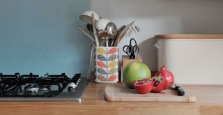 organized kitchen countertop with utensils in a storage pot beside the hob