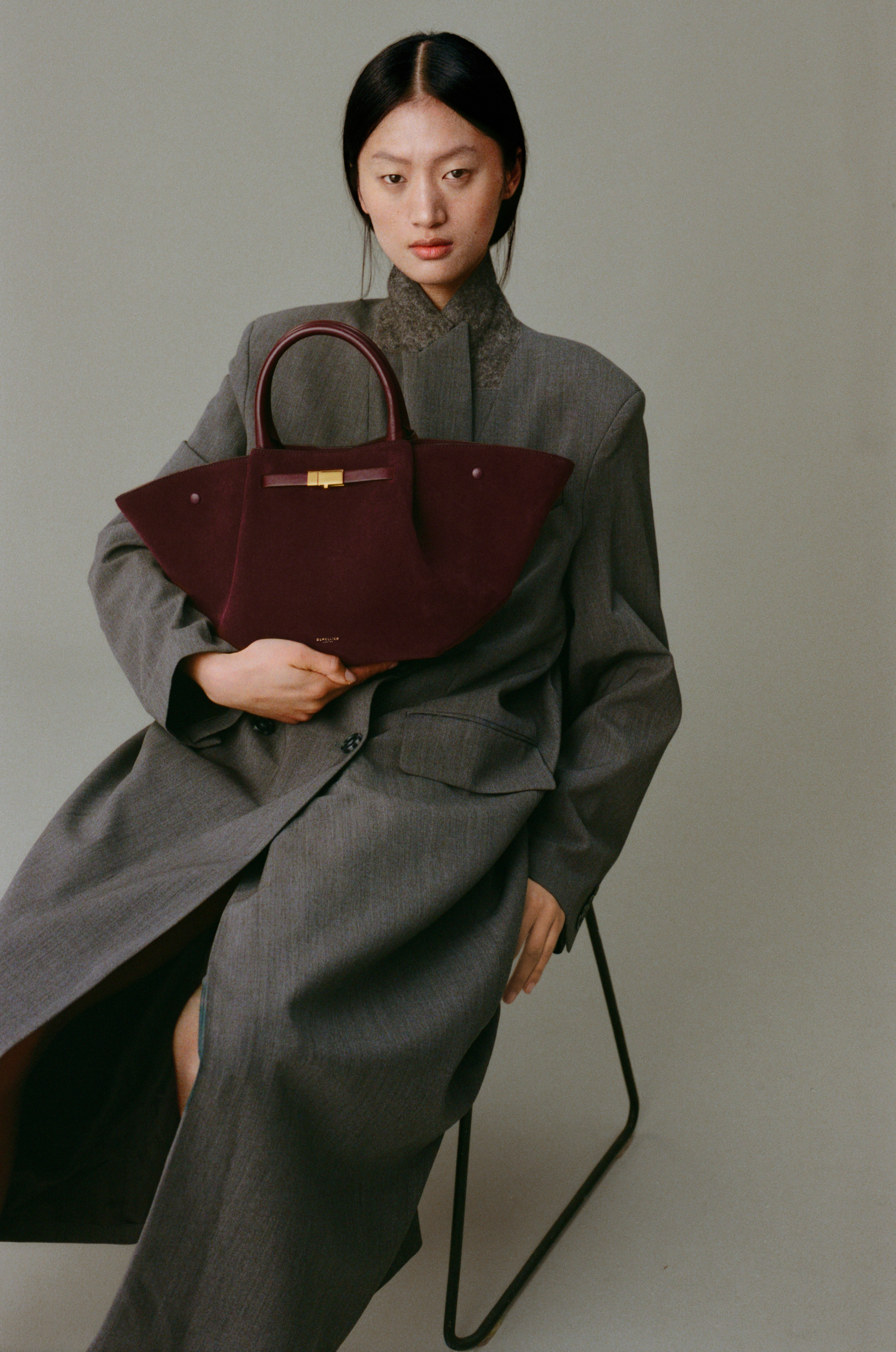 a model carries the demellier Midi New York Burgundy Suede Smooth bag
