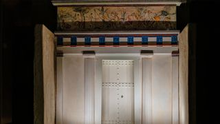 A reconstruction of a tomb with a white facade and a painting on top.