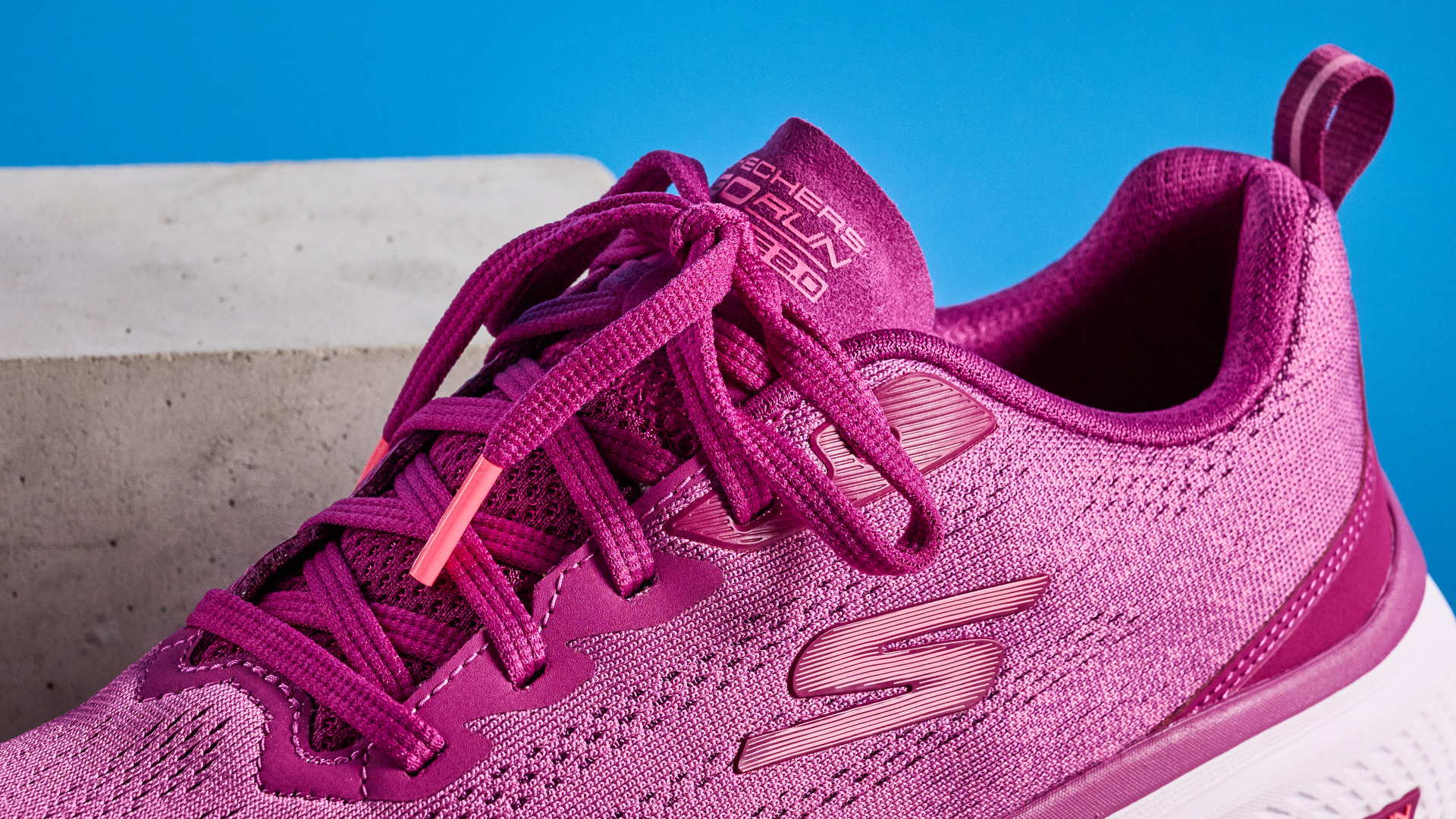 the skechers go run elevate 2.0 running shoes in the women's style, in fuchsia pink, photographed against a blue background