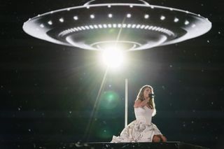 Taylor Swift onstage performing in front of a UFO