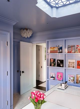 a purple home office with a magazine wall and tulips on the desk