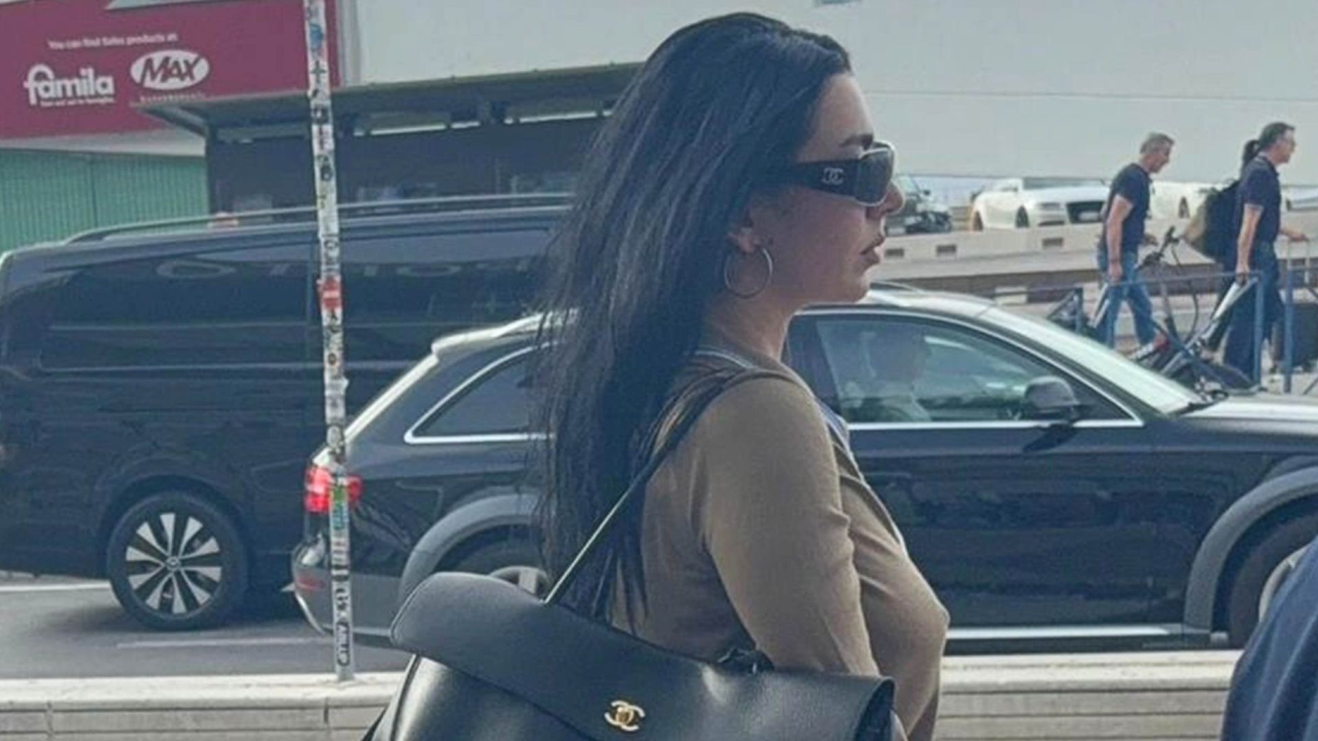 Charli XCX gets of an airplane wearing black flared jeans with heels pointed-toe boots and a large Chanel bag.