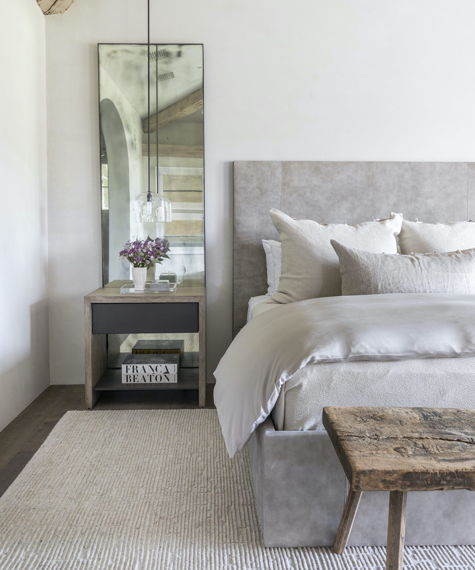 neutral bedroom with mirrors behind bedside table