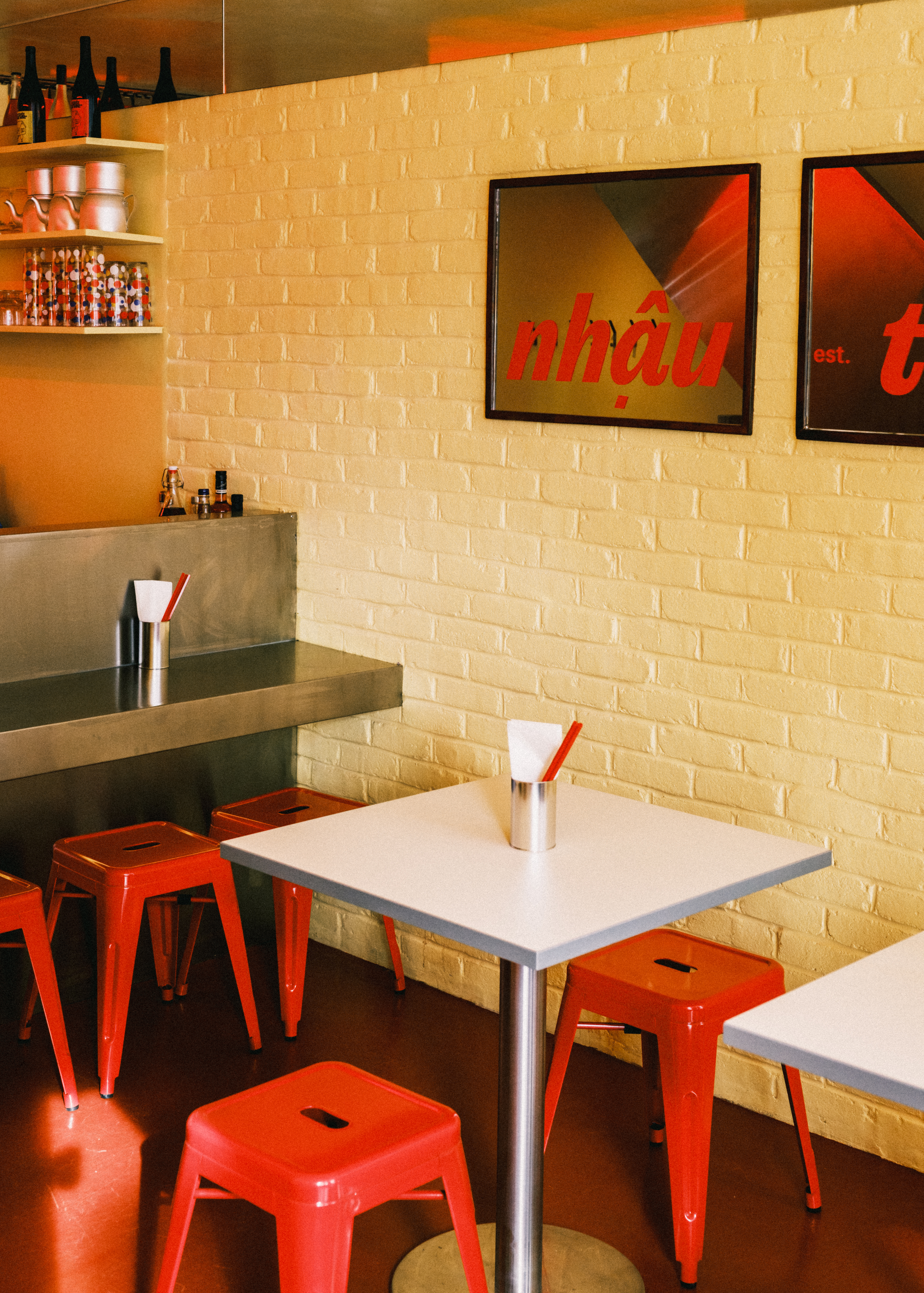 An inventively designed, small eatery boasts buttery brick walls, sleek green floors, red banquettes and metal chairs, and spherical, softly glowing opaque glass sconces.