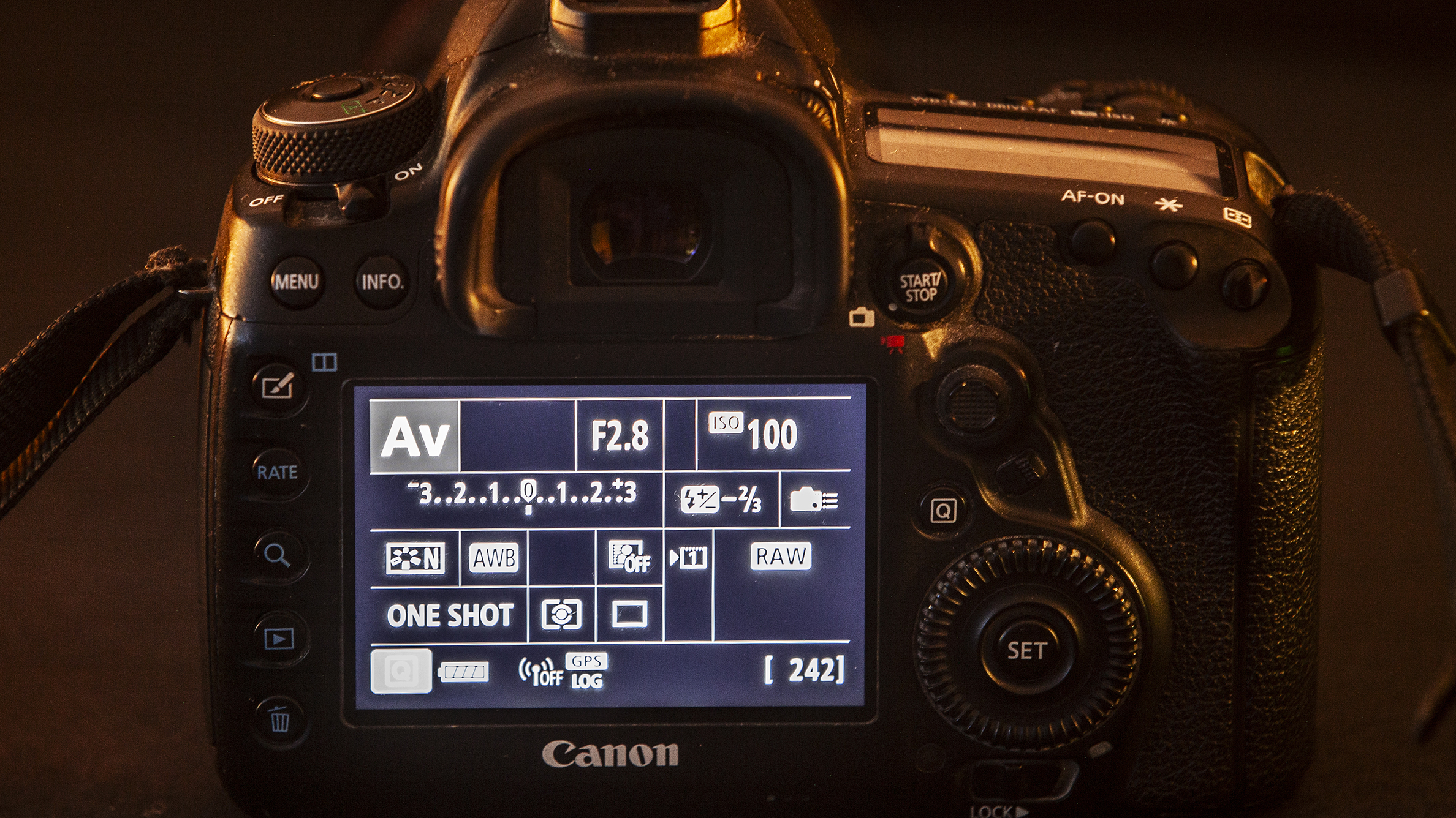 Close-up of a DSLR camera&#039;s back, showcasing its LCD screen with camera settings. Buttons and dials are visible, conveying functionality and precision