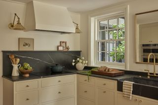 A kitchen with beige cabinets and dark backsplash