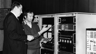 Peter Lawo and an employee look at an early sound processor in a black and white picture.