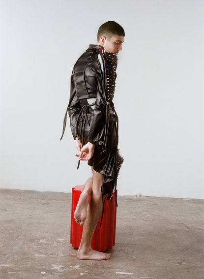 Person in Ottolinger studded outfit on stool