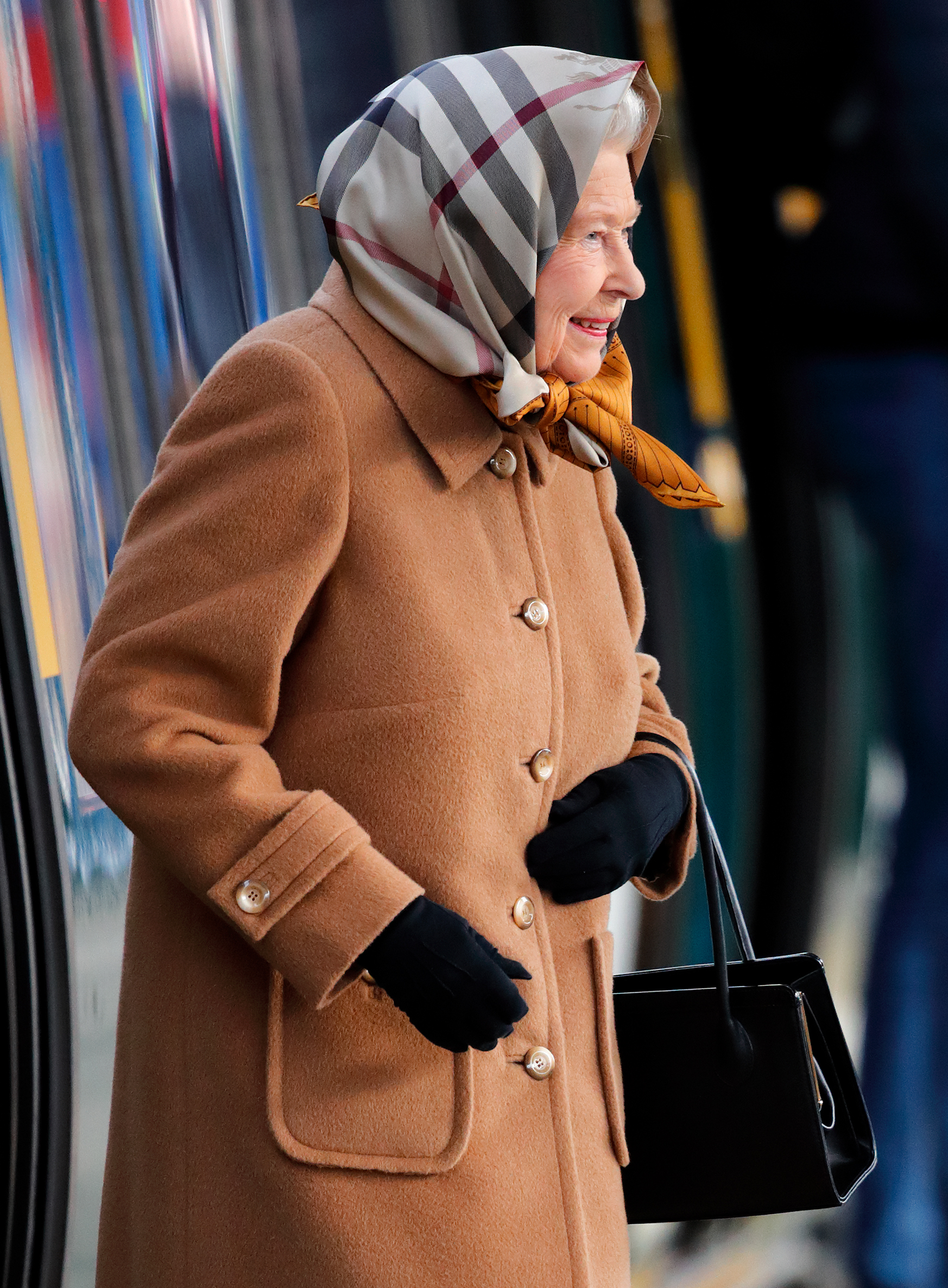 Queen Elizabeth wearing a tan coat and burberry check head scarf
