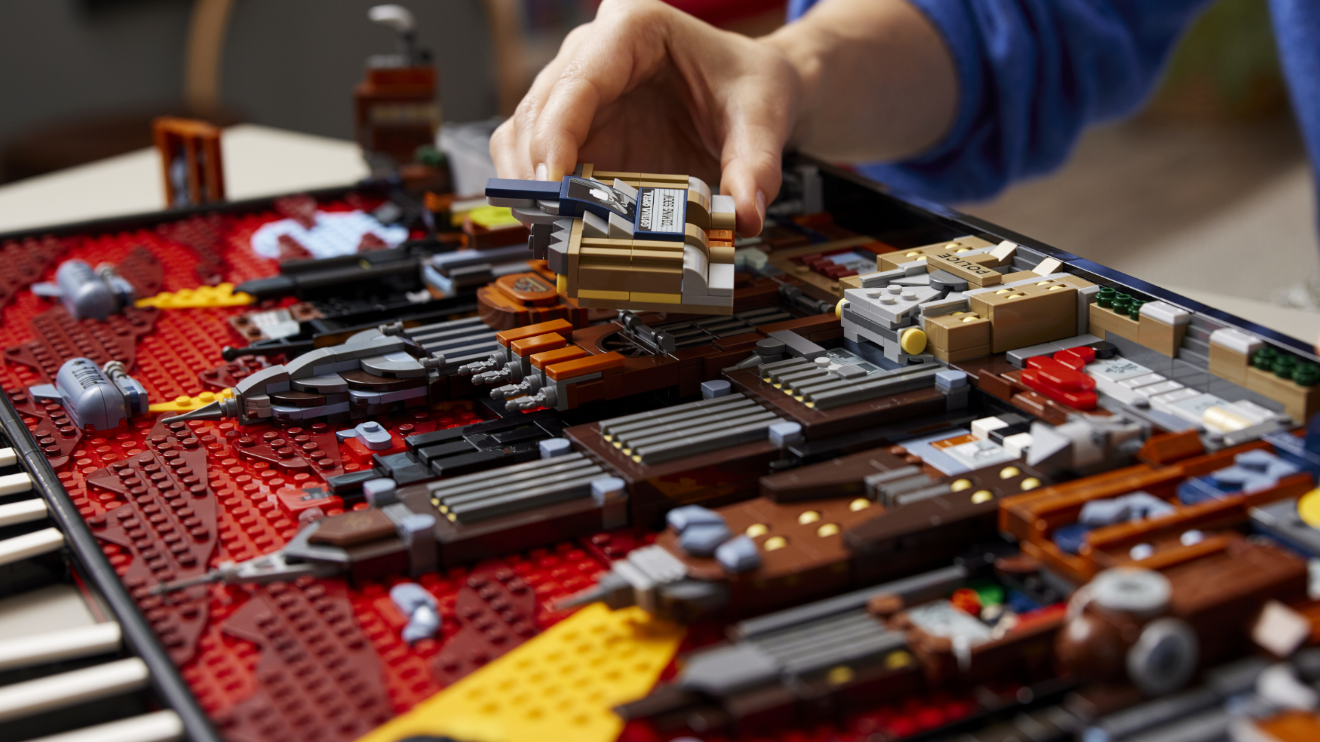 A hand places a piece of Lego Gotham City