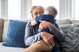 A grandmother hugging a young boy while sat on the sofa