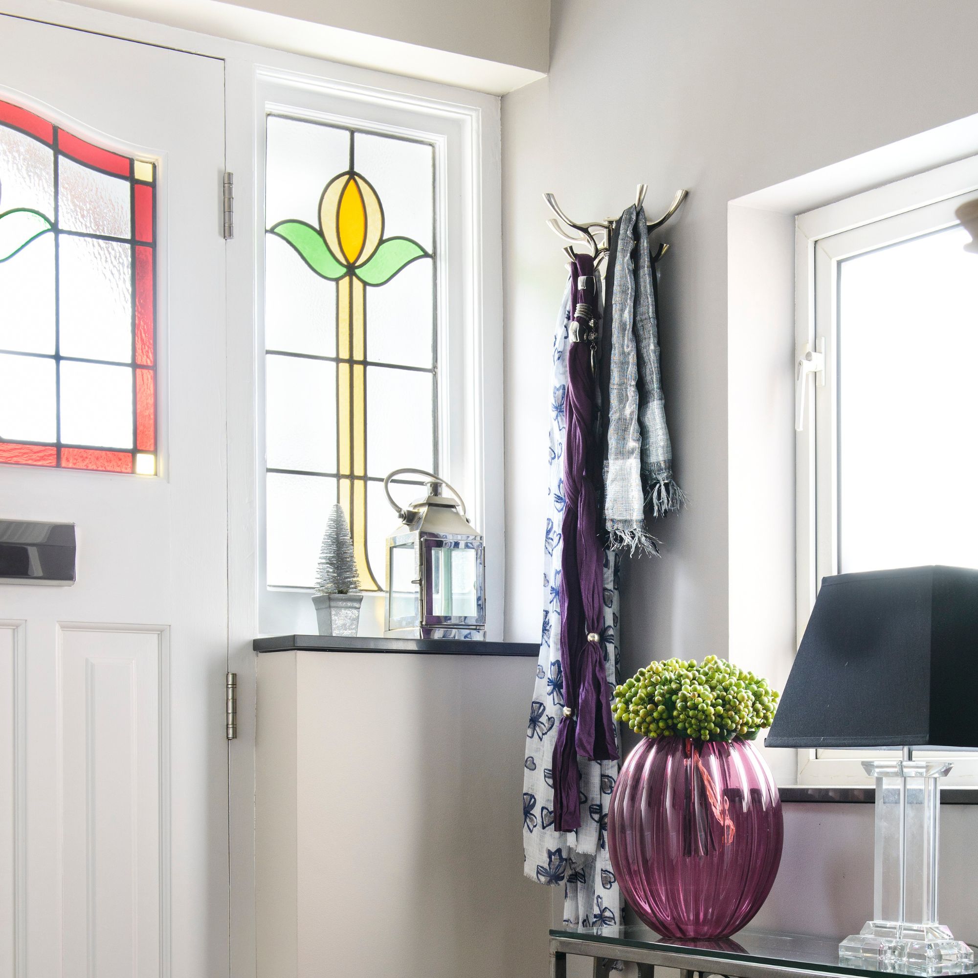 A white front door with stained glass detailing and a slim stained glass window to the side