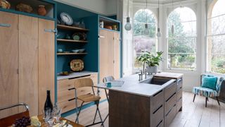 rustic wooden kitchen with blue walls and large arched windows