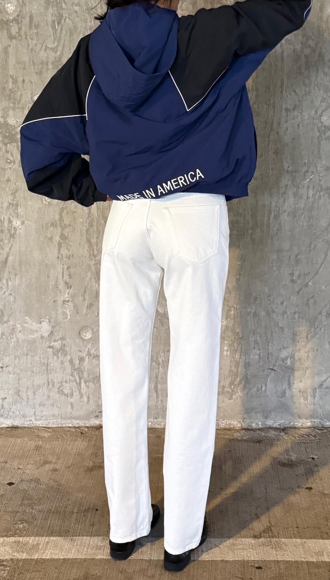 Kendall Jenner wearing a Marty Supreme navy blue windbreaker with white jeans and black loafers.