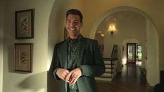 matt rogers as Greg Boycelane as he smiles and wears a suit while standing in the morgan home in no good deed