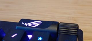 A black ASUS ROG Strix Scope II RX gaming keyboard on a wooden desk