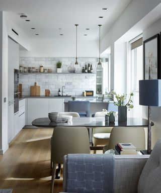 L-shaped kitchens illustrated in a narrow white room with white cabinetry and blue textile accents.