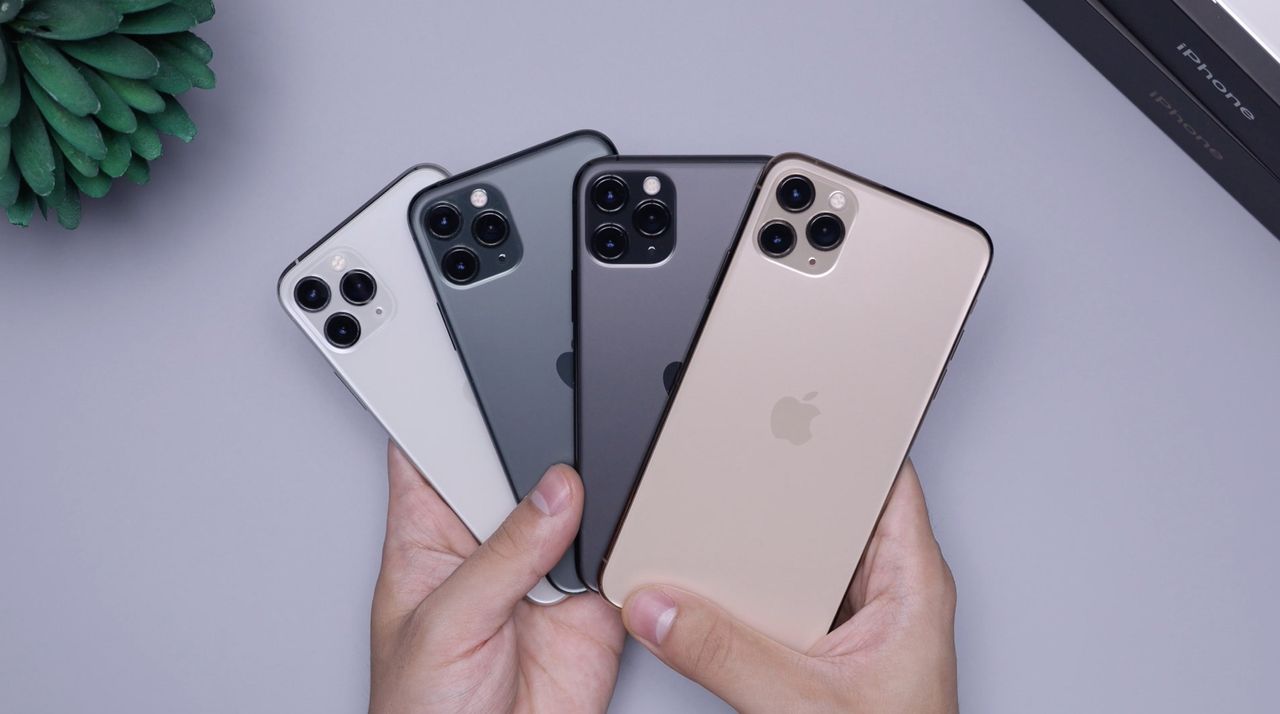 A selection of iPhones held over a desk