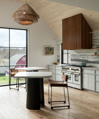 Kitchen with neutral cabinets and backsplash, bar tables and stools and wood floor