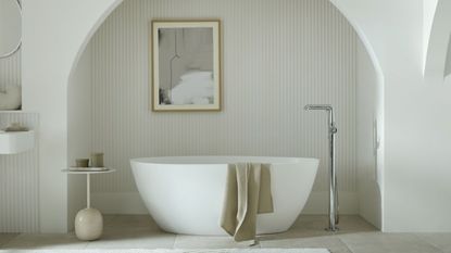 All white bathroom with a curved free standing tub in an alcove