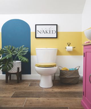 Bright colored bathroom with pink and yellow, black frames and white toilet